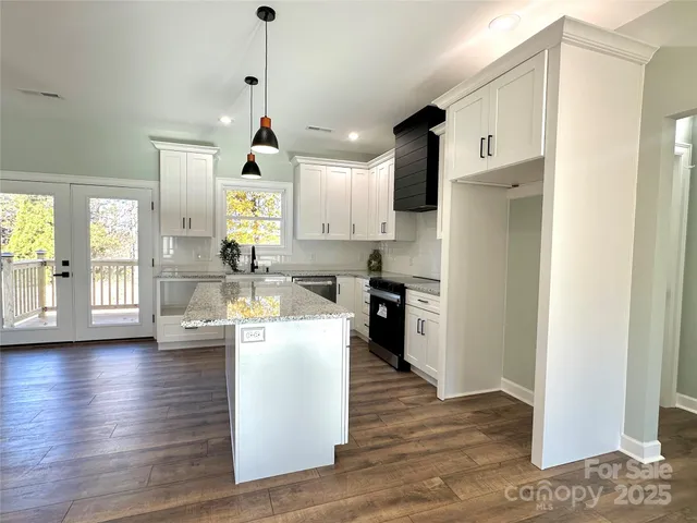 a kitchen with kitchen island granite countertop wooden floors and a refrigerator