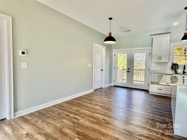 a view of an empty room with window and wooden floor