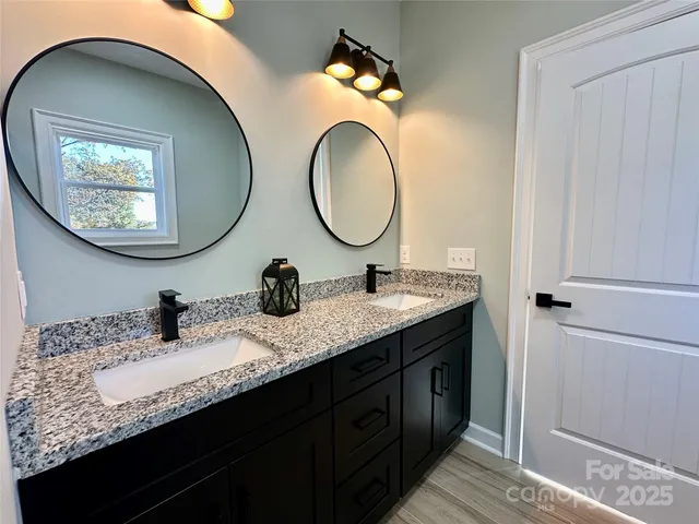 a bathroom with a granite countertop double vanity sink and a mirror