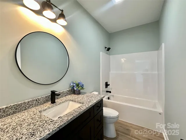 a bathroom with a granite countertop toilet a sink and a mirror