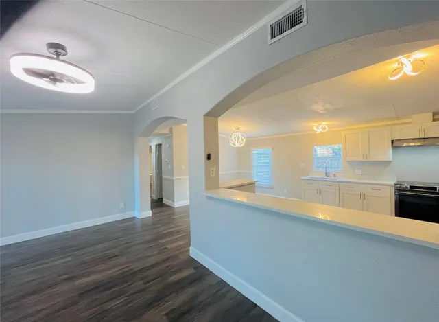 a large white kitchen with a sink and dishwasher a stove top oven with wooden floor