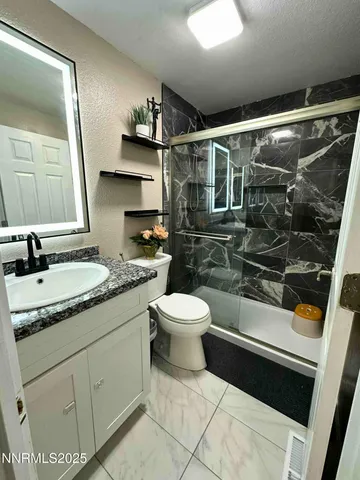 a bathroom with a granite countertop sink toilet and shower
