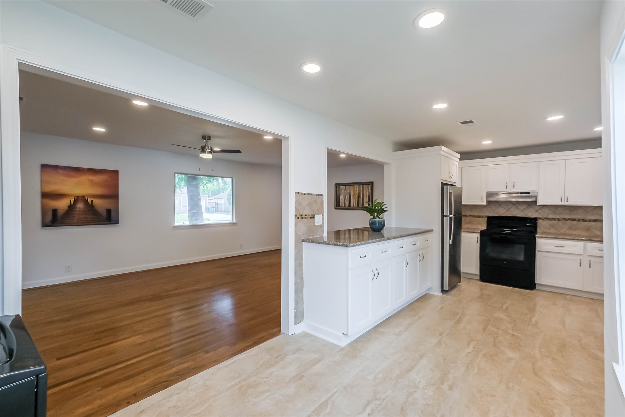 7543 Greenstone Street Houston, TX 77087 - Photo 2 of 24 a large white kitchen with kitchen island a sink dishwasher a stove and a refrigerator with wooden floor