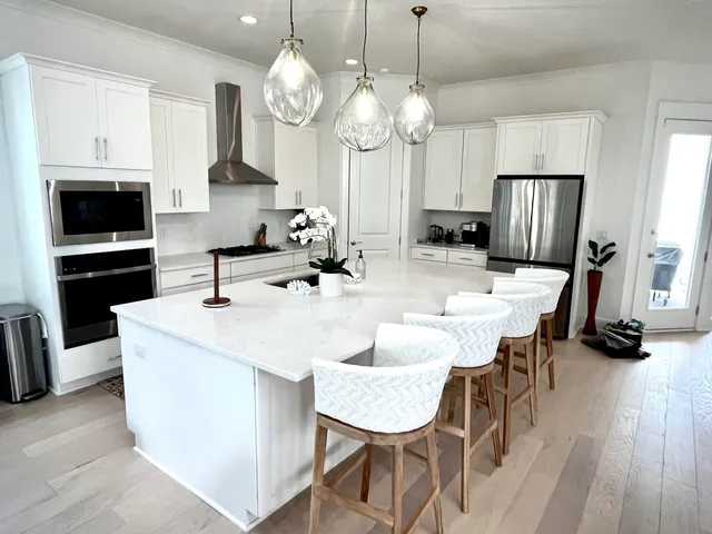 a large kitchen with kitchen island a stove a sink a dining table and chairs with wooden floor