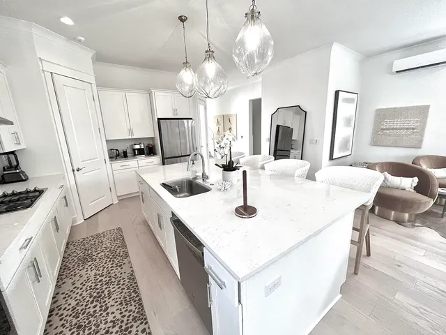 a kitchen with granite countertop a sink a stove top oven a dining table and chairs