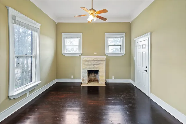 a view of a livingroom with wooden floor a fireplace and windows