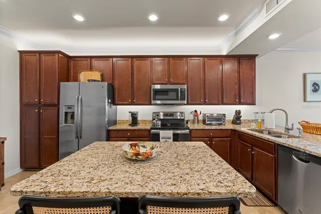 a kitchen with granite countertop a sink counter space and stainless steel appliances