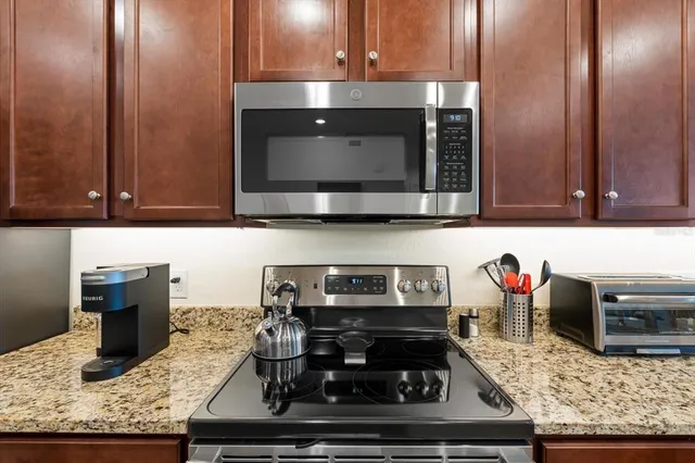 a kitchen with stainless steel appliances granite countertop a table chairs sink and cabinets