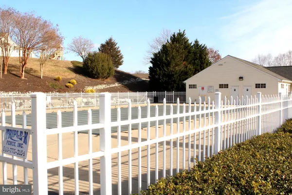 a view of a white house with a small yard and wooden fence