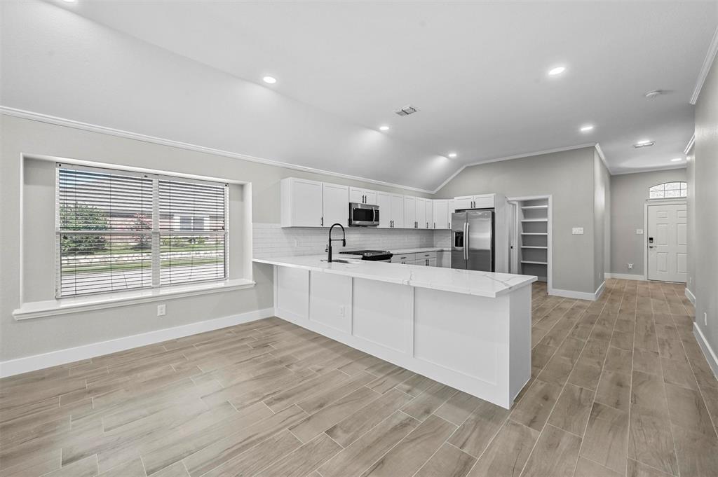 2667 Lake Ridge Drive Little Elm, TX 75068 - Photo 6 of 17 a large white kitchen with kitchen island a stove a sink dishwasher a oven with white cabinets and wooden floor