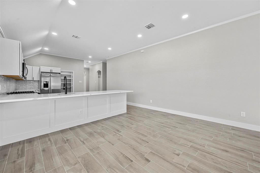 2667 Lake Ridge Drive Little Elm, TX 75068 - Photo 7 of 17 a large white kitchen with kitchen island a sink wooden floor and a refrigerator