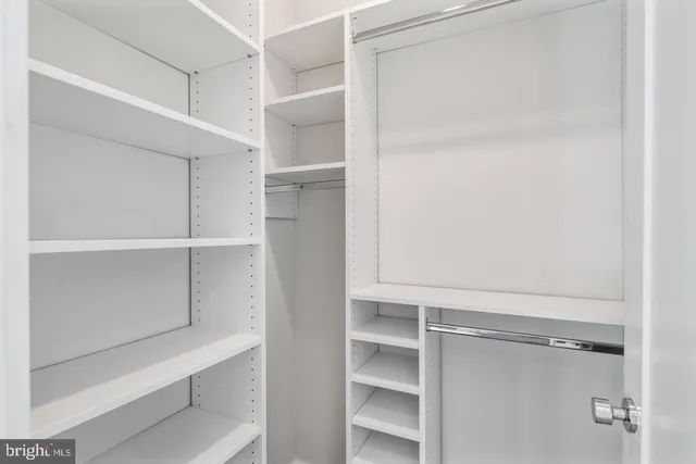 a view of walk in closet with empty racks