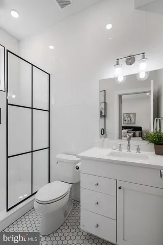 a bathroom with a toilet a sink a mirror a shower a vanity and window