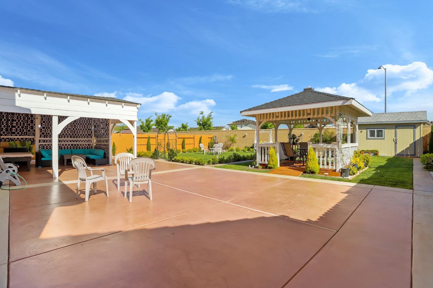 2925 Fuchsia Drive Lodi, CA 95242 - Photo 37 of 44 a view of a patio with a table and chairs under an umbrella with wooden fence