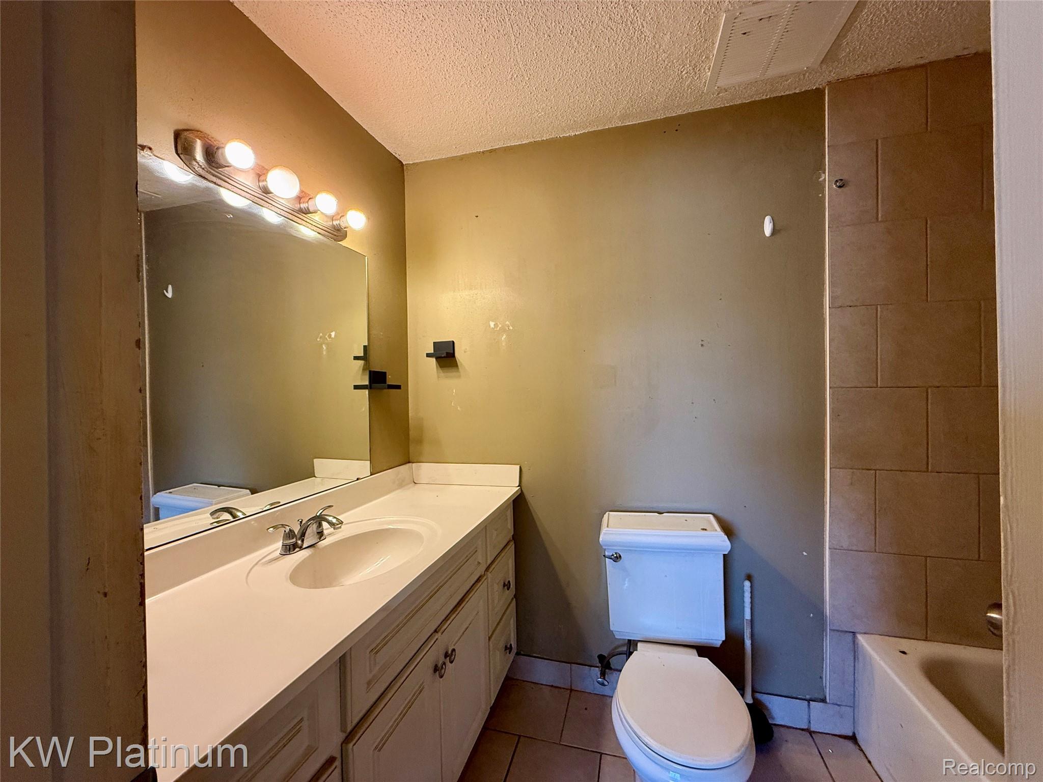 8214 24 Mile Road Utica, MI 48316 - Photo 10 of 14 Bathroom with vanity, a textured ceiling, light tile patterned floors, and shower / tub combination