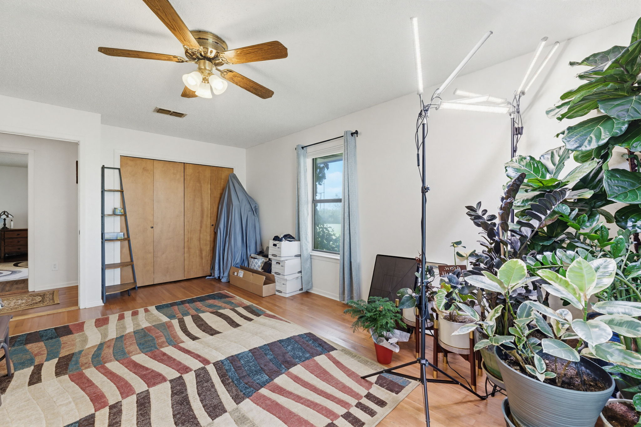 120 Rae Lane Jarrell, TX 76537 - Photo 28 of 40 Room featuring wood-finish flooring, a ceiling fan with integrated lighting, a window with a light blue curtain, and a double-door closet with wood-panel doors