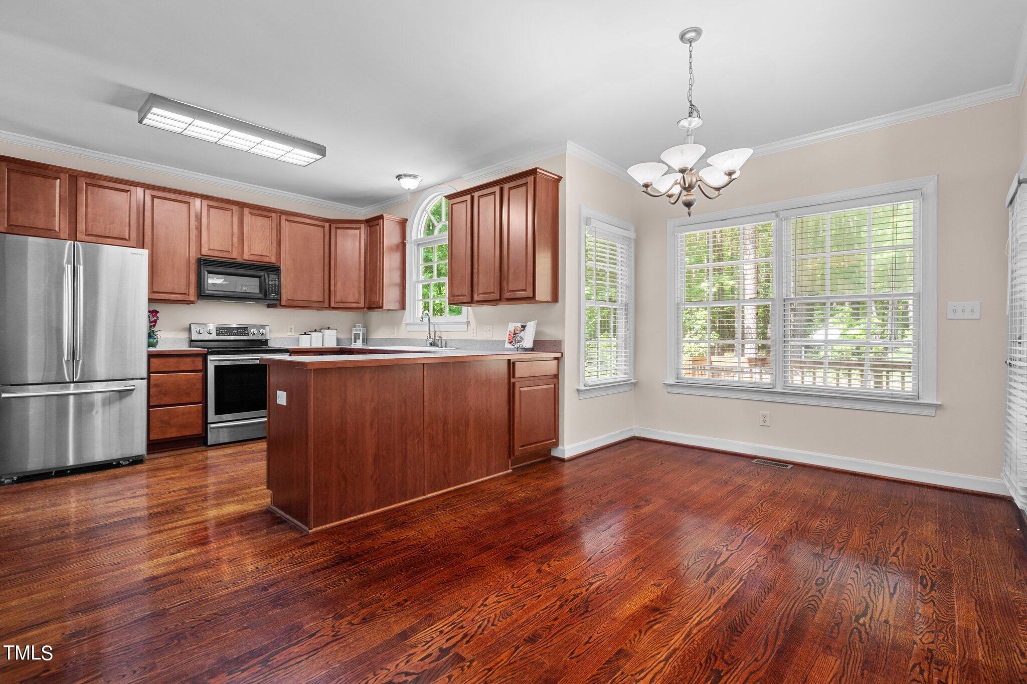 2404 Sunnystone Way Raleigh, NC 27613 - Photo 25 of 51 a kitchen with stainless steel appliances granite countertop wooden floors and white cabinets