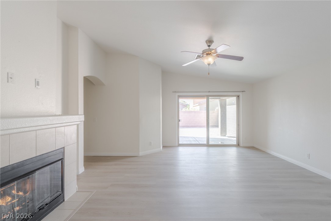 8079 Buffalo Ranch Avenue Las Vegas, NV 89147 - Photo 6 of 29 A spacious layout showcases a tiled fireplace and sliding glass doors leading outdoors.