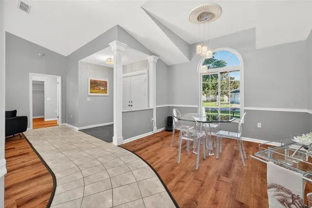 a kitchen with a refrigerator a stove top oven and a dining table with wooden floor