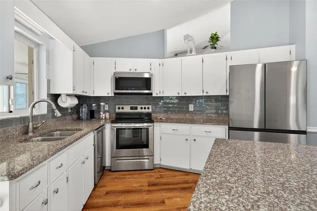 a kitchen with granite countertop a sink a stove and microwave
