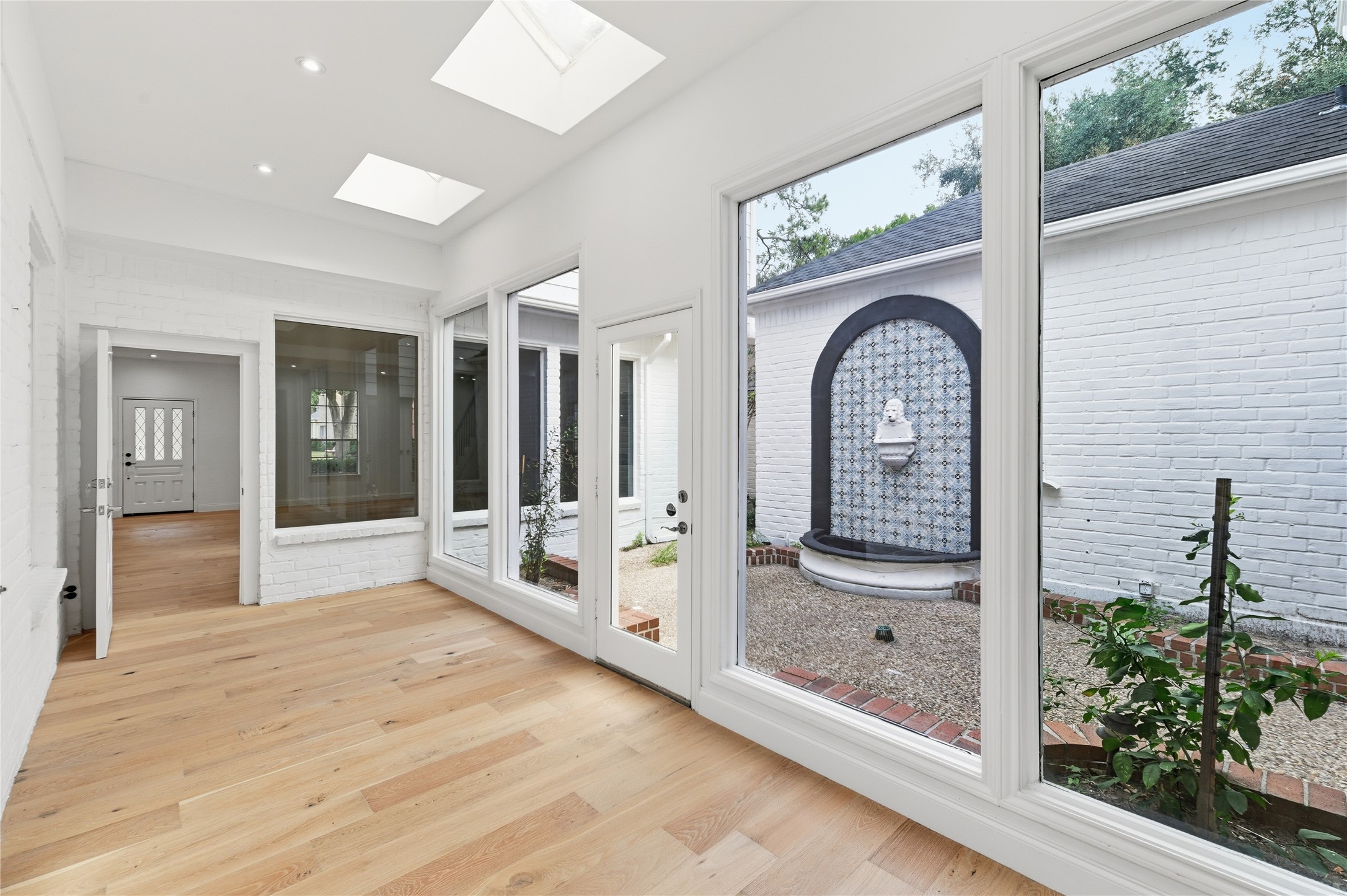 15827 Foxgate Road Houston, TX 77079 - Photo 14 of 37 Stunning sunroom with skylights and floor-to-ceiling windows overlooking a private courtyard and decorative fountain. A serene indoor-outdoor retreat for morning coffee or quiet relaxation
