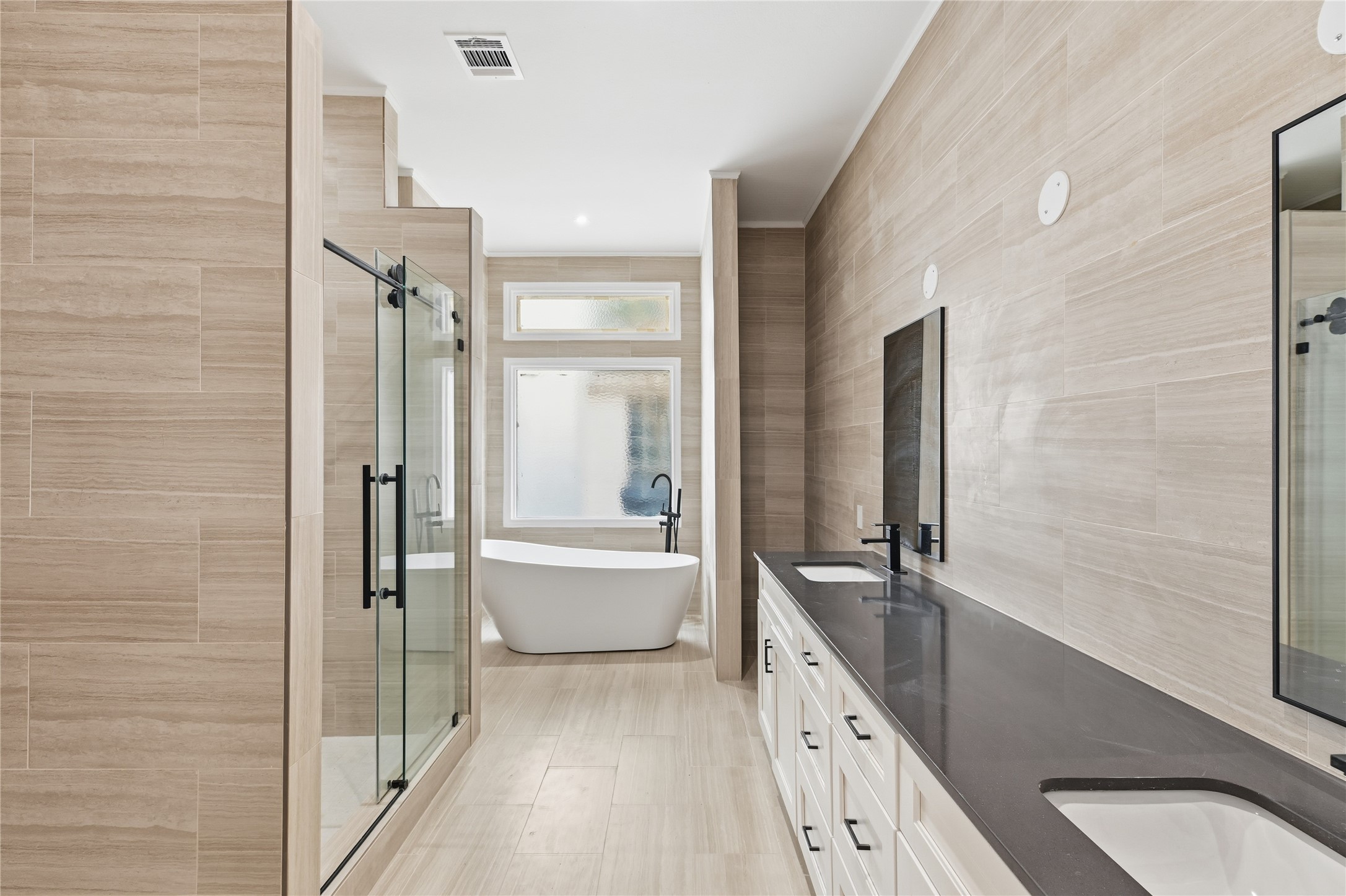 15827 Foxgate Road Houston, TX 77079 - Photo 20 of 37 Designer primary bath featuring a freestanding soaking tub, oversized walk-in shower, and dual vanities with sleek black fixtures. Floor to ceiling tiles adds a spa like feel to this luxurious retreat.