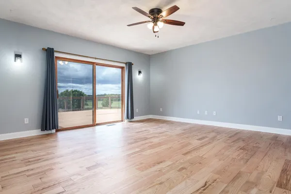 an empty room with chandelier fan and windows