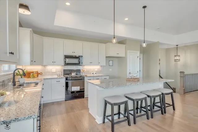 a kitchen with kitchen island a dining table chairs sink and white appliances