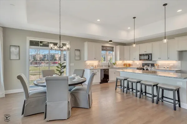 a dining room with stainless steel appliances kitchen island granite countertop a dining table chairs and a chandelier