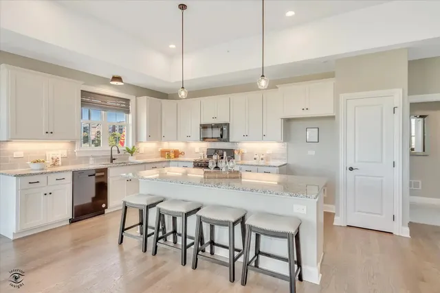 a kitchen with kitchen island granite countertop a table chairs sink and cabinets