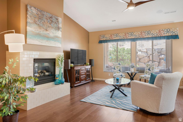 1587 Whitestone Drive St. George, UT 84790 - Photo 13 of 36 Spacious living area featuring wood-finish flooring, a tiled fireplace with a stone surround, and large windows with blinds and valances
