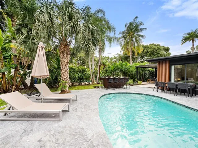a view of a swimming pool with lawn chairs under an umbrella