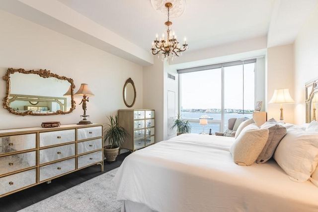 a bedroom with a bed a chandelier and dresser