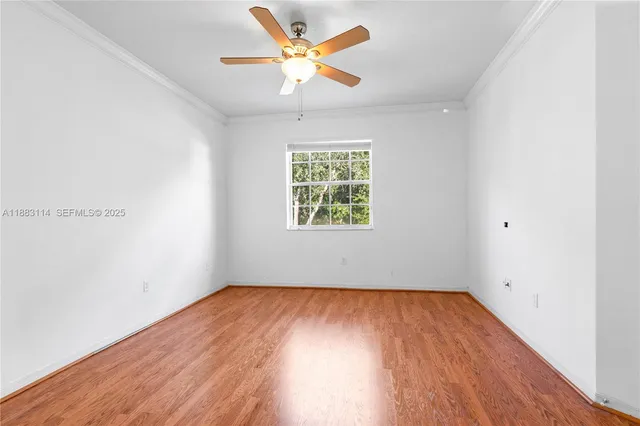 an empty room with wooden floor ceiling fan and windows