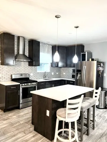 a kitchen with stainless steel appliances kitchen island granite countertop a dining table and chairs