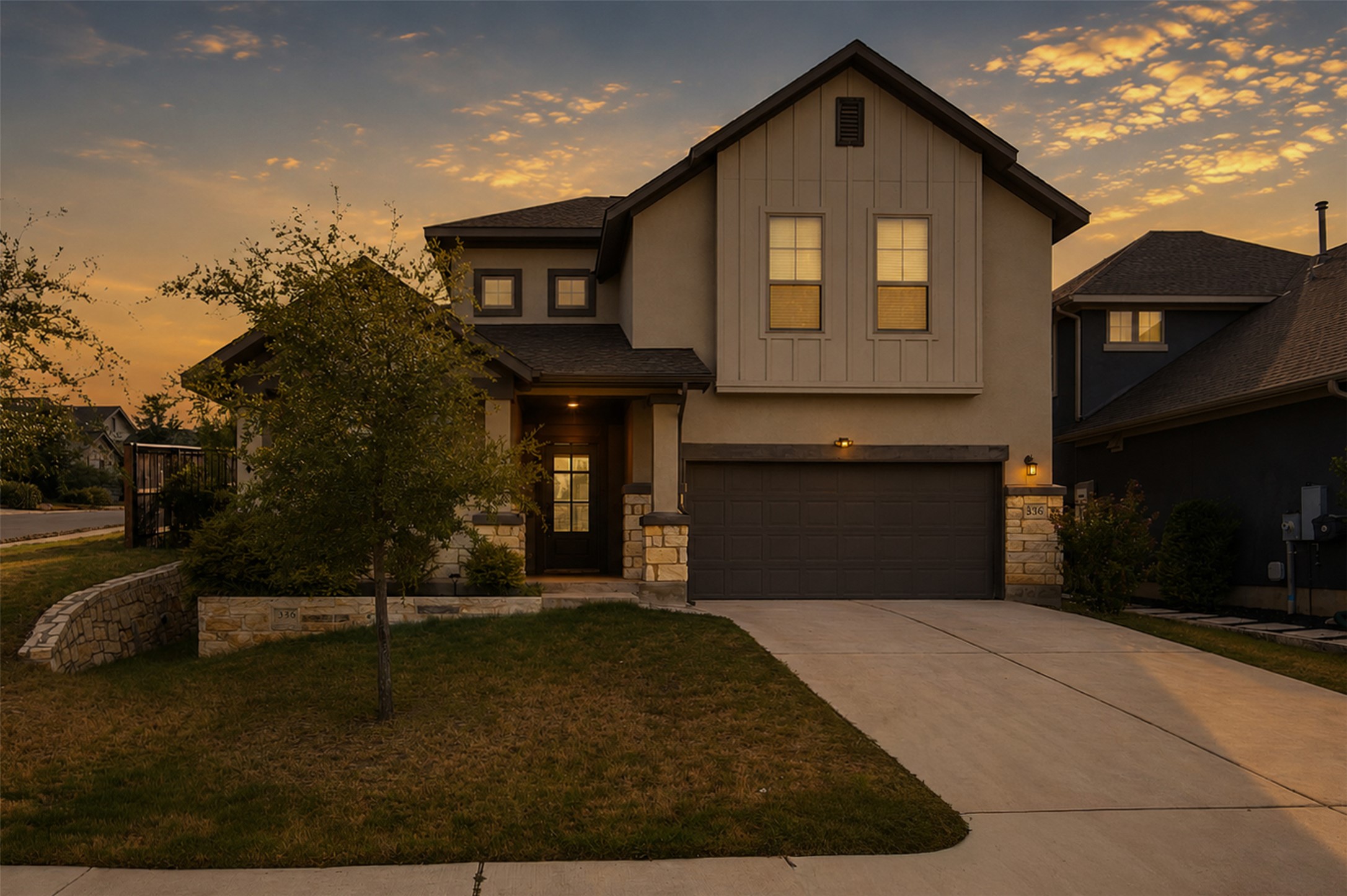Craftsman architectural details blend stone and siding elements along a wide concrete driveway.