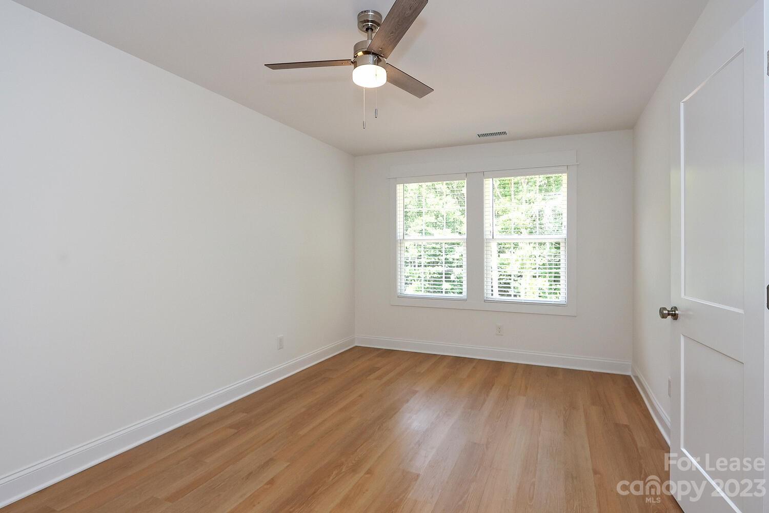 8710 Island Point Road Sherrills Ford, NC 28673 - Photo 29 of 48 an empty room with wooden floor ceiling fan and windows