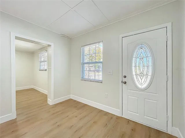 an empty room with wooden floor a mirror and a window