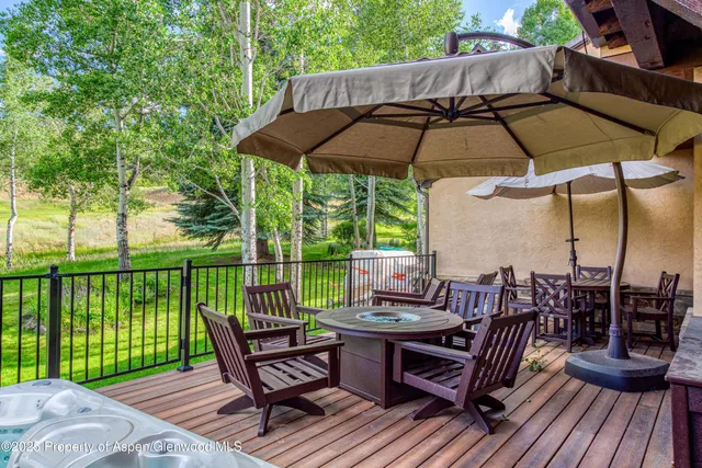 a view of a roof deck with table and chairs under an umbrella with wooden floor