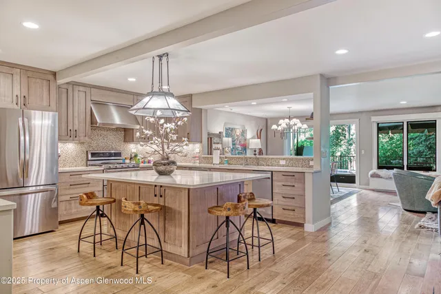 a kitchen with stainless steel appliances granite countertop a dining table chairs refrigerator and cabinets