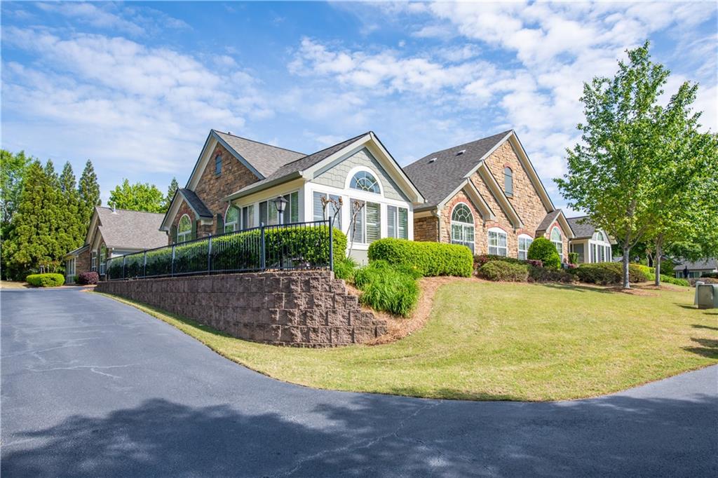 a front view of a house with a yard and trees in the background