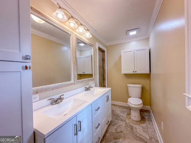 a spacious bathroom with a double vanity sink toilet and a mirror