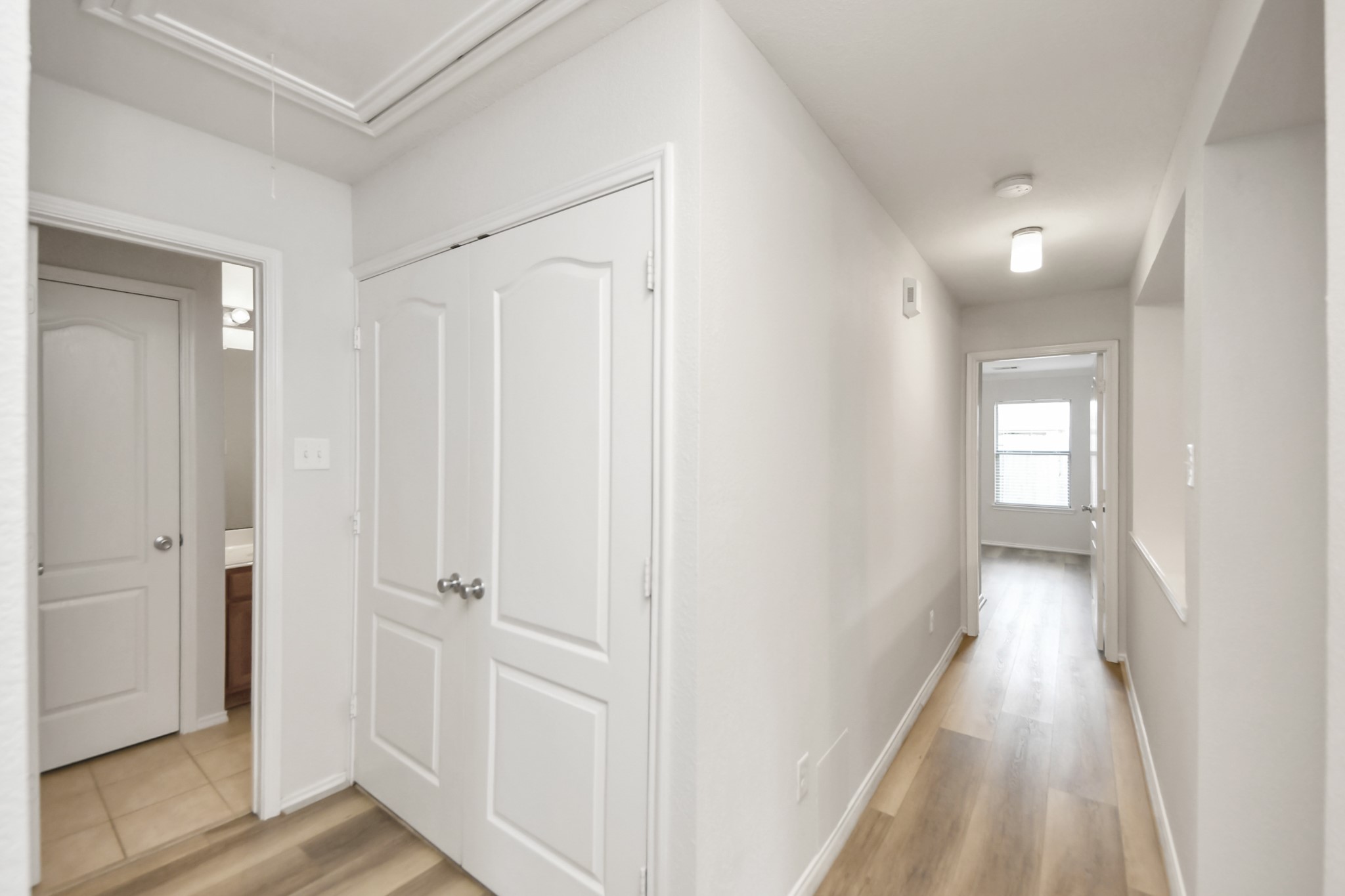 2930 Ribbon Creek Way Spring, TX 77389 - Photo 8 of 25 Bright hallway with sleek wood flooring, leading to a sunlit room. Features ample closet space and access to a modern bathroom.