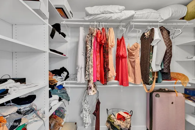 a view of walk in closet with clothes and shoes