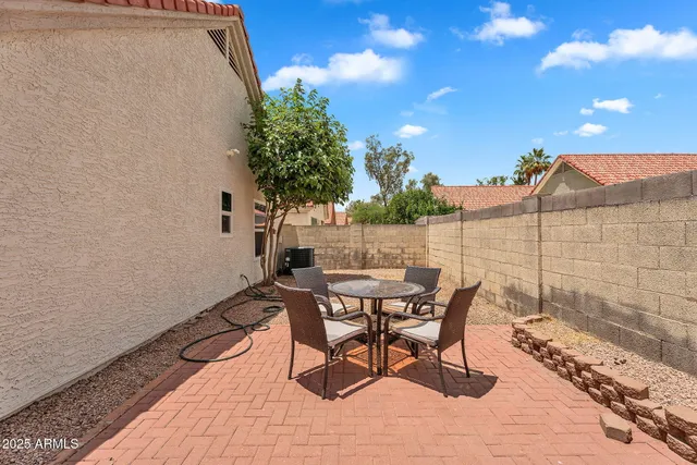 a patio with table and chairs and potted plants