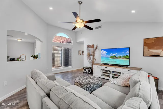 a living room with furniture and a flat screen tv with kitchen view