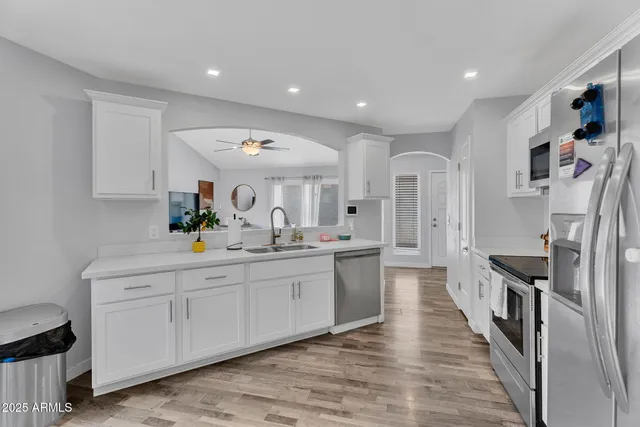 a large white kitchen with stainless steel appliances lots of counter space and wooden floor