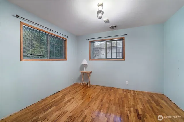 a view of an empty room with window and wooden floor