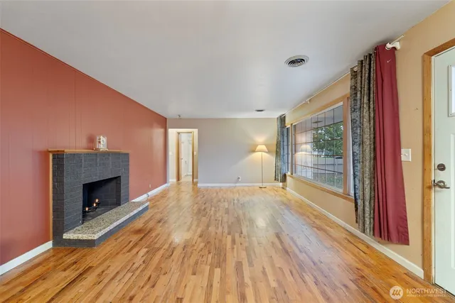 a view of empty room with wooden floor and fireplace