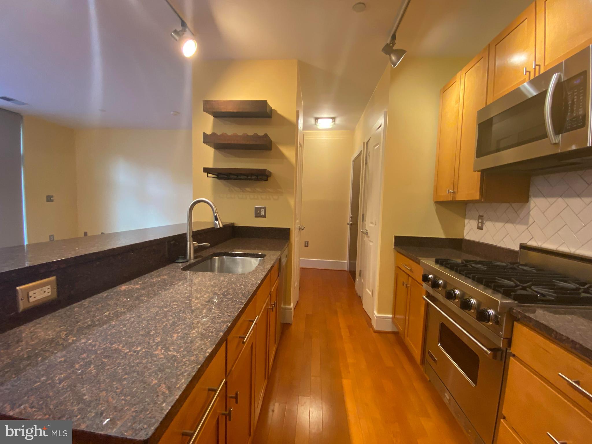 1654 Euclid Street Northwest, Unit 105 Washington, DC 20009 - Photo 7 of 29 a kitchen with stainless steel appliances granite countertop a sink a stove and a wooden floors